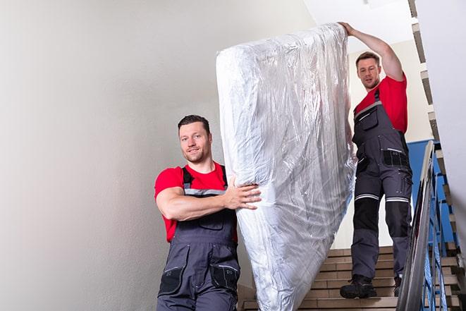 team of workers maneuvering a box spring through a doorway in Irwindale